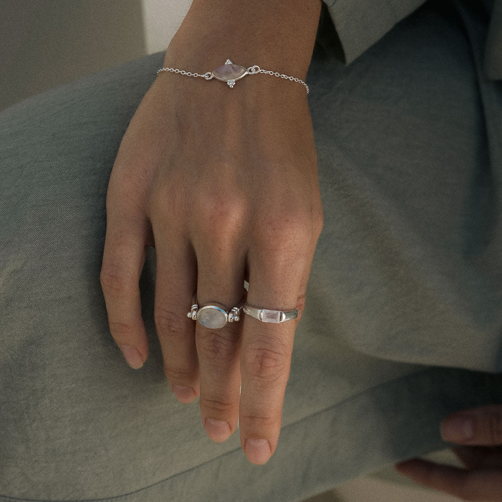 Hand wearing silver rings on a green fabric background