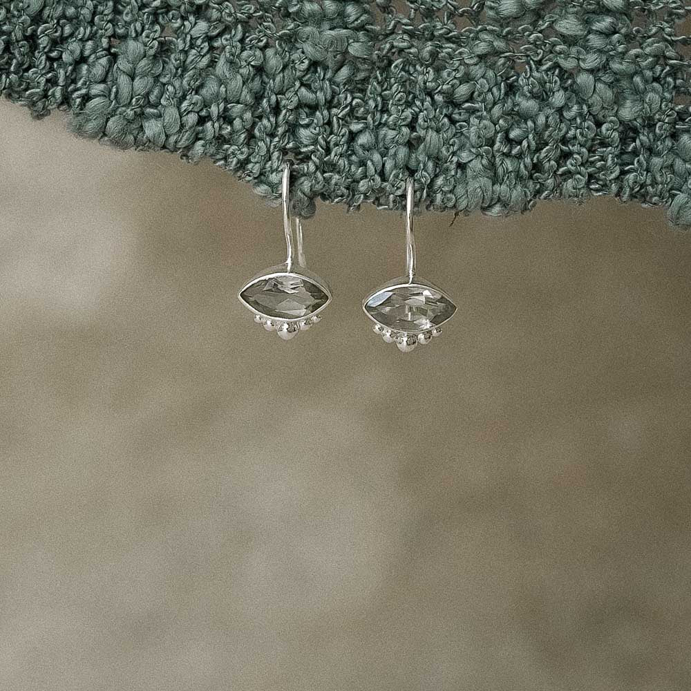 Green Amethyst (Prasiolite) earrings hanging from a textured green surface