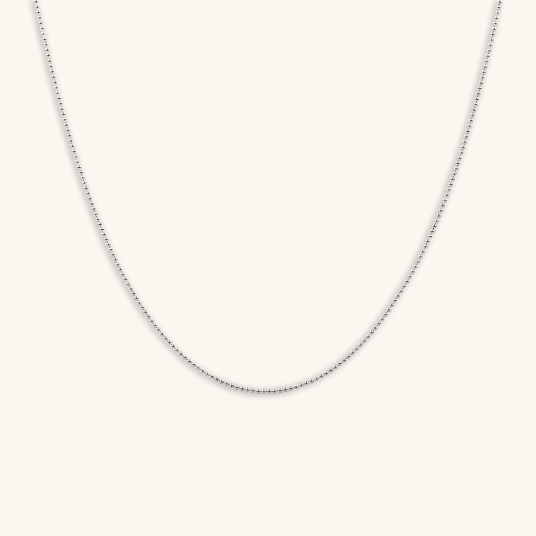 Silver ball chain necklace on a light grey background