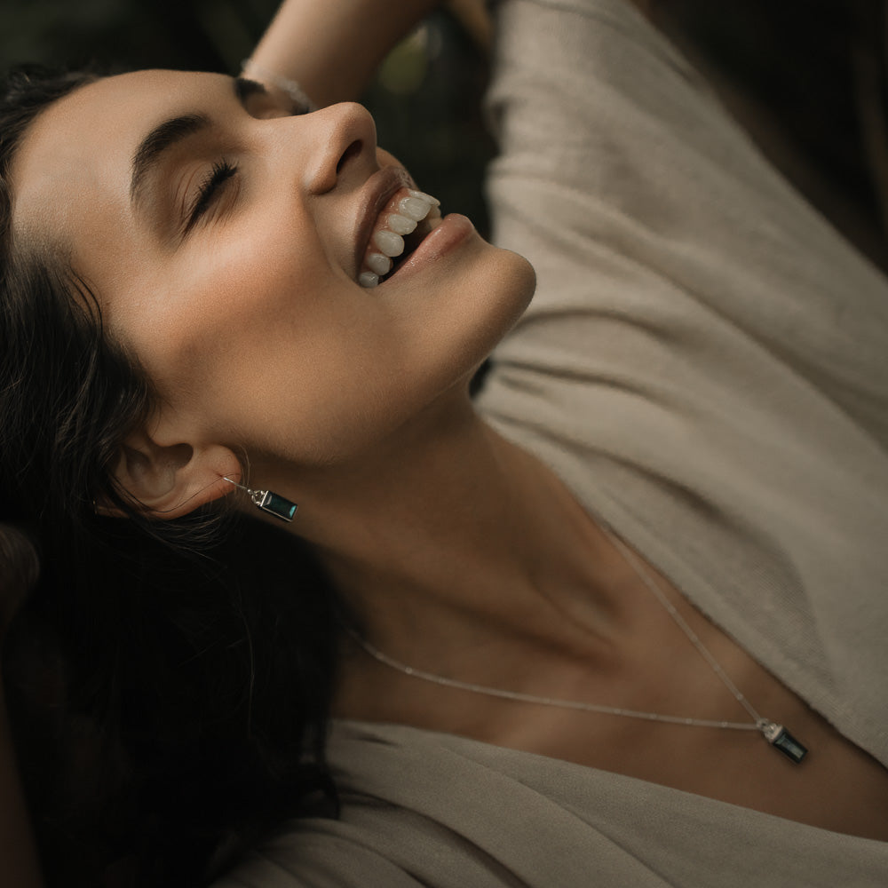 a smiling happy woman wearing baguette labradorite silver earrings in the jungle