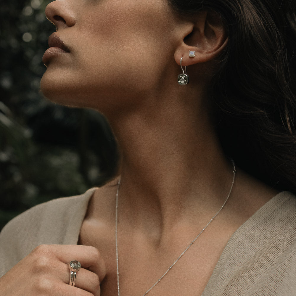 woman wearing square gemstone moonstone studs and green amethyst earrings