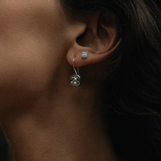 a woman wearing a pair of green amethyst square faceted earrings and ring