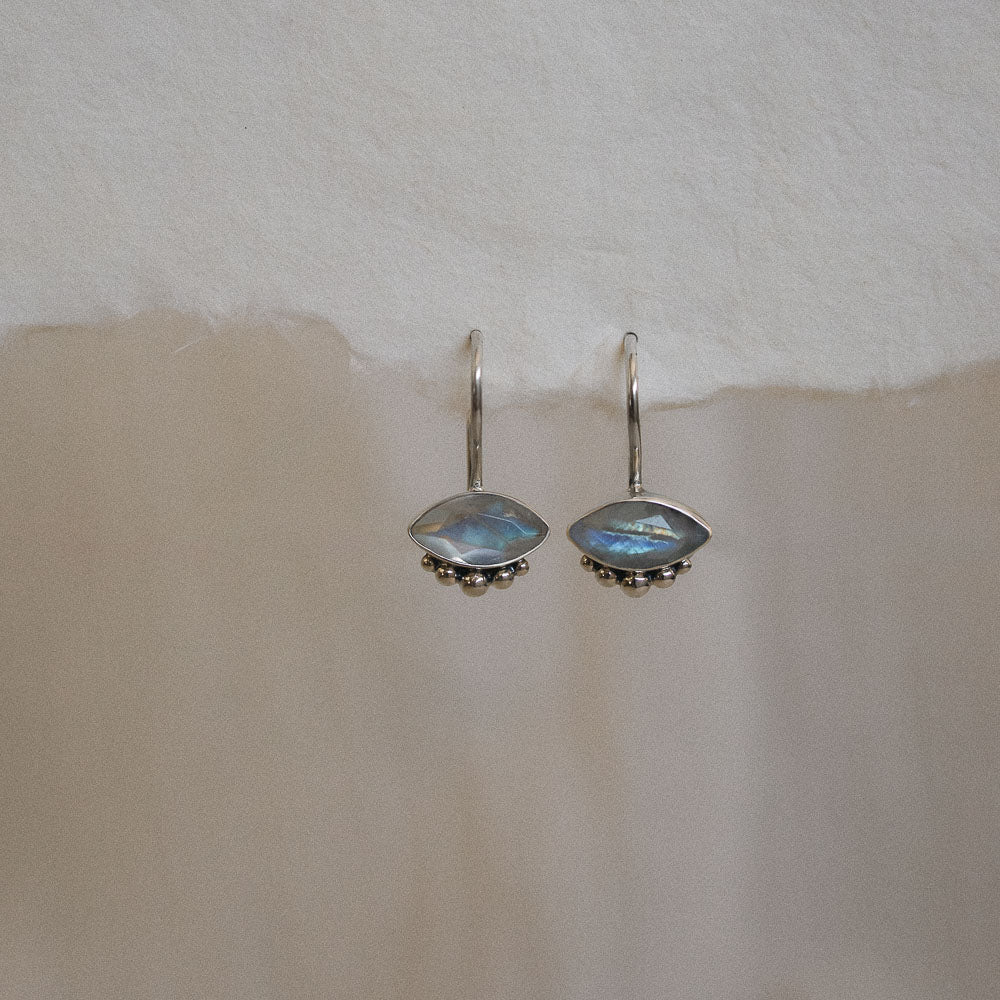 a pair of marquise moonstone gemstone earrings hanging from handmade paper