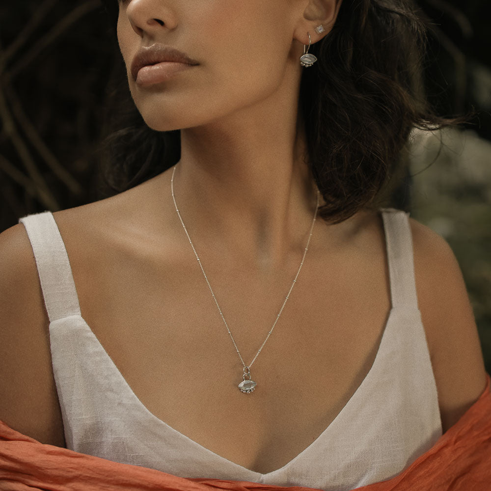 a woman wearing a silver satellite necklace chain and marquise moonstone pendant
