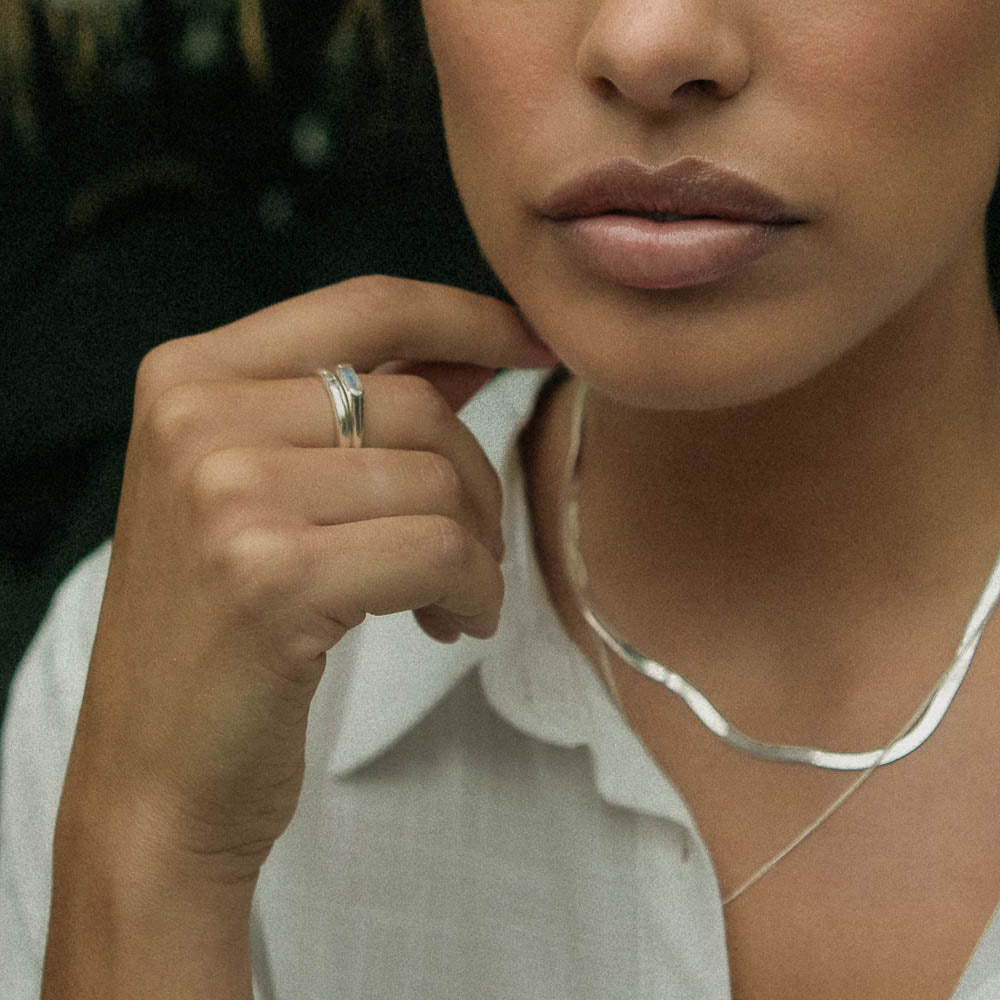 a woman wearing a moonstone baguette ring and sterling silver necklace chains