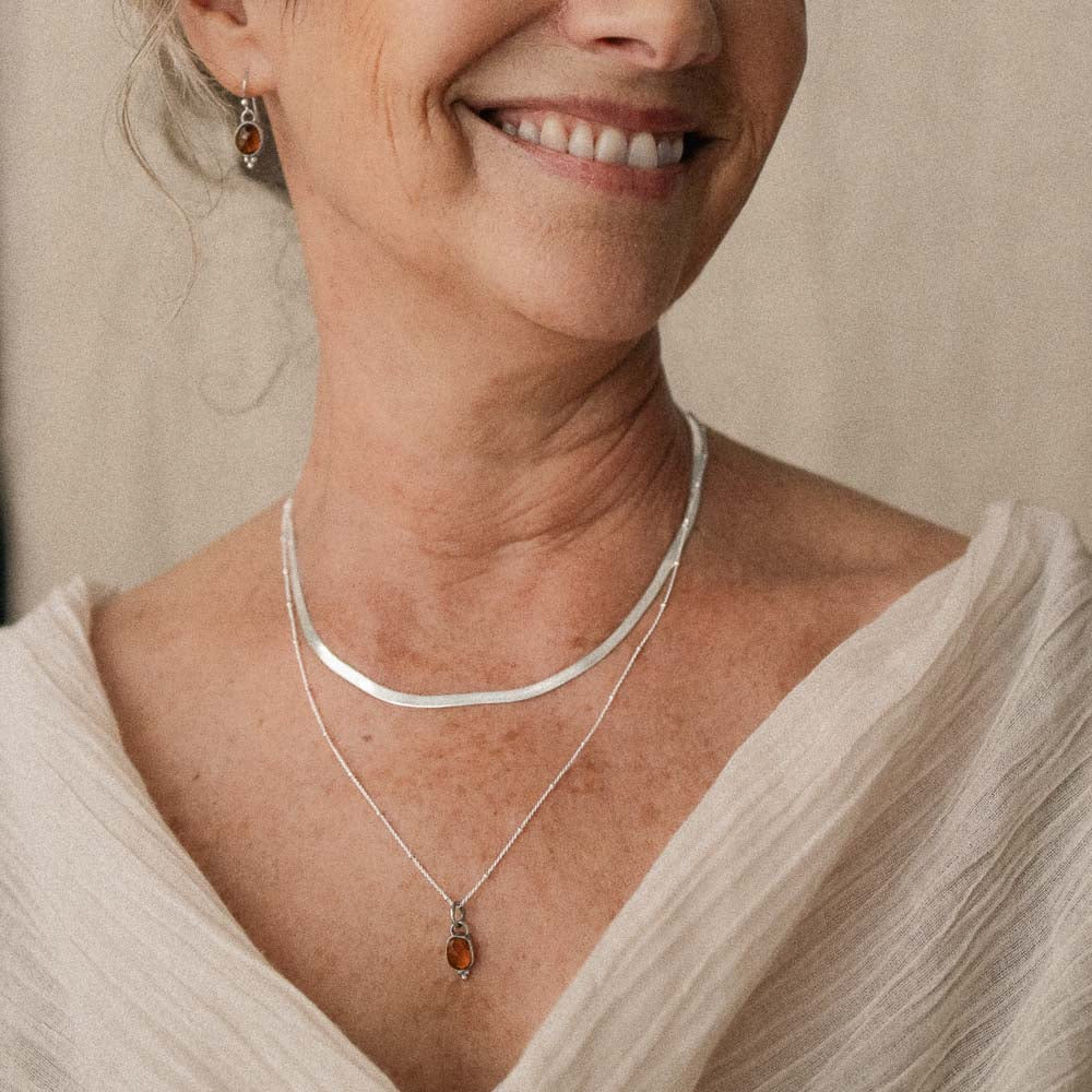 woman wearing an orange tourmaline pendant on satellite chain