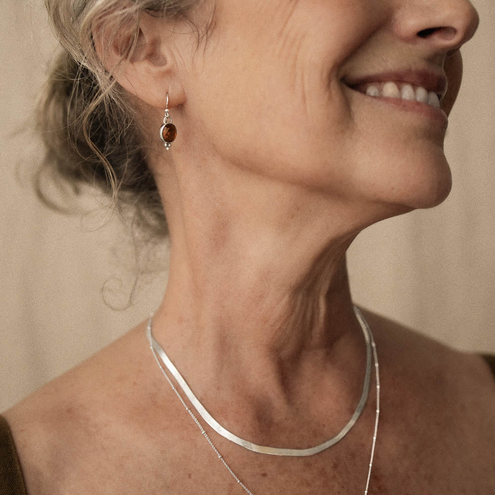 smiling woman wearing orange tourmaline earrings