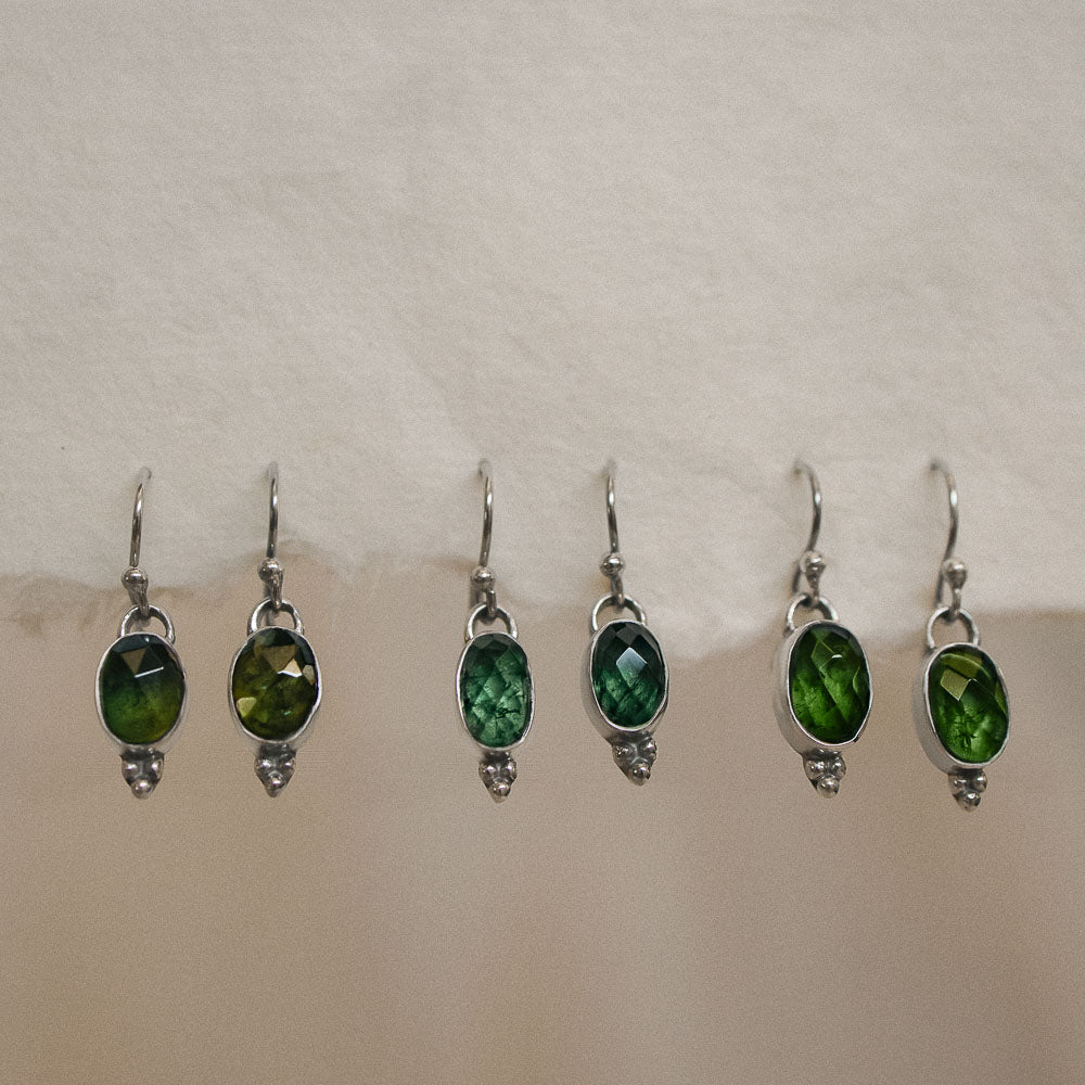 pairs of green tourmaline earrings on handmade paper