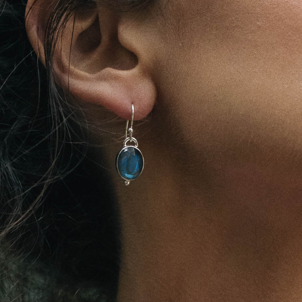 blue flashing oval labradorite earring closeup on a model's ear