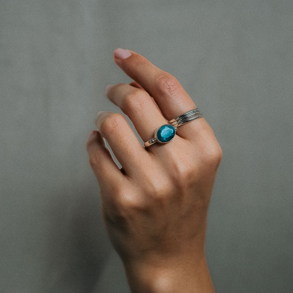 a silver oval gemstone labradorite ring and silver stacker rings on finger