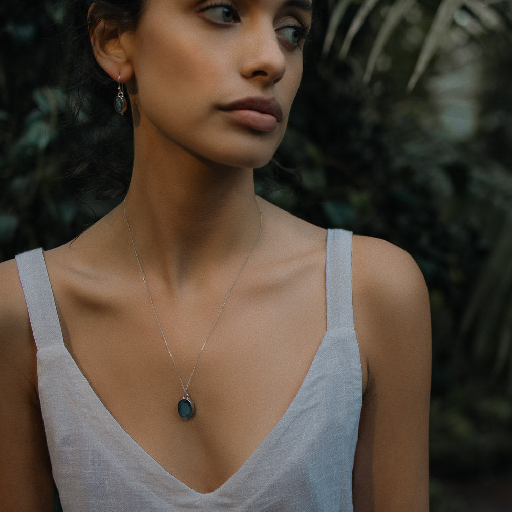 a symbolic oval gemstone labradorite pendant on model in the jungle