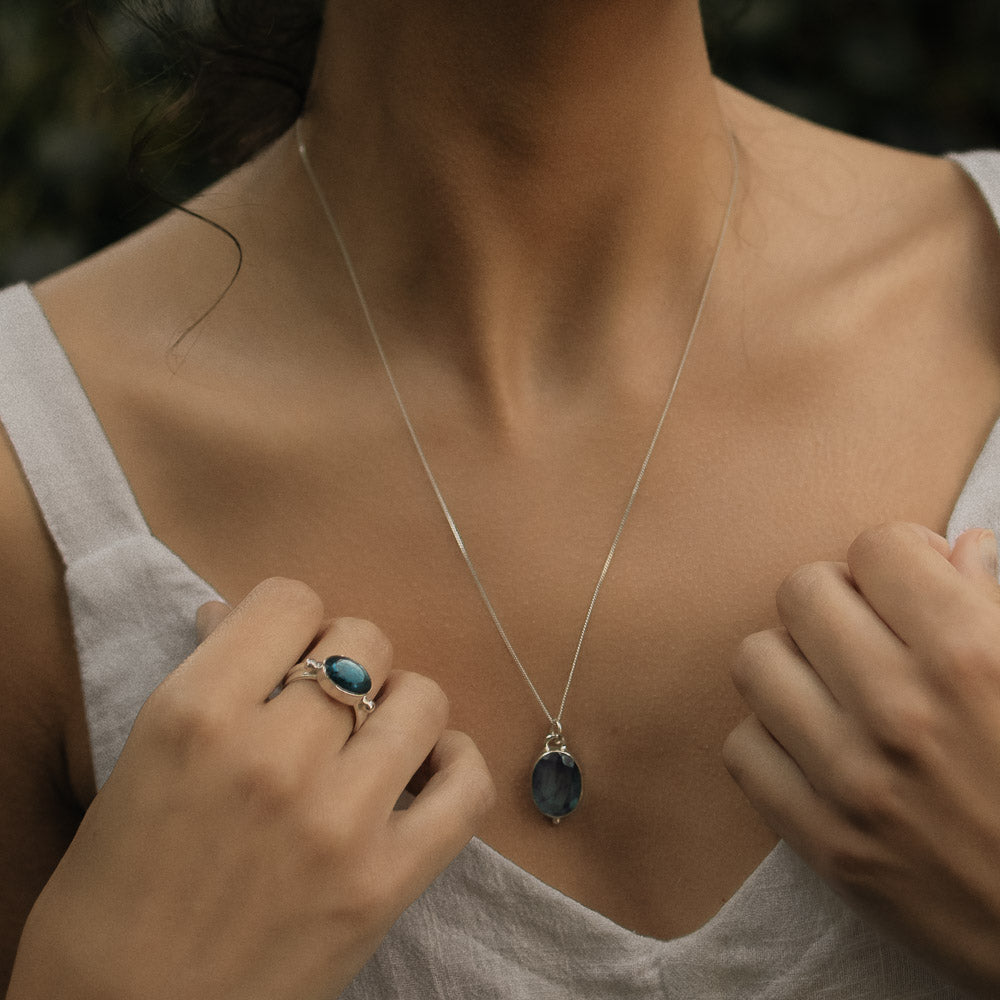 model wearing silver oval labradorite pendant and ring in a rainforest