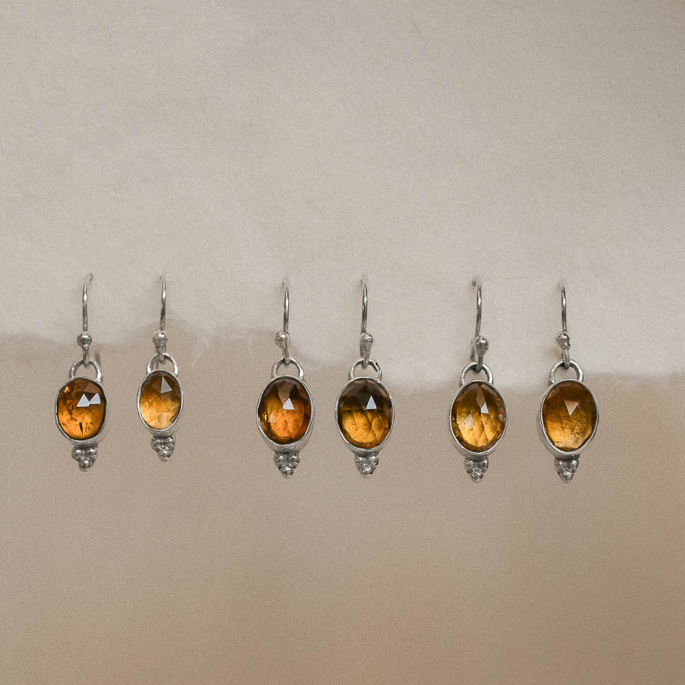 pairs of orange tourmaline earrings hanging on handmade paper