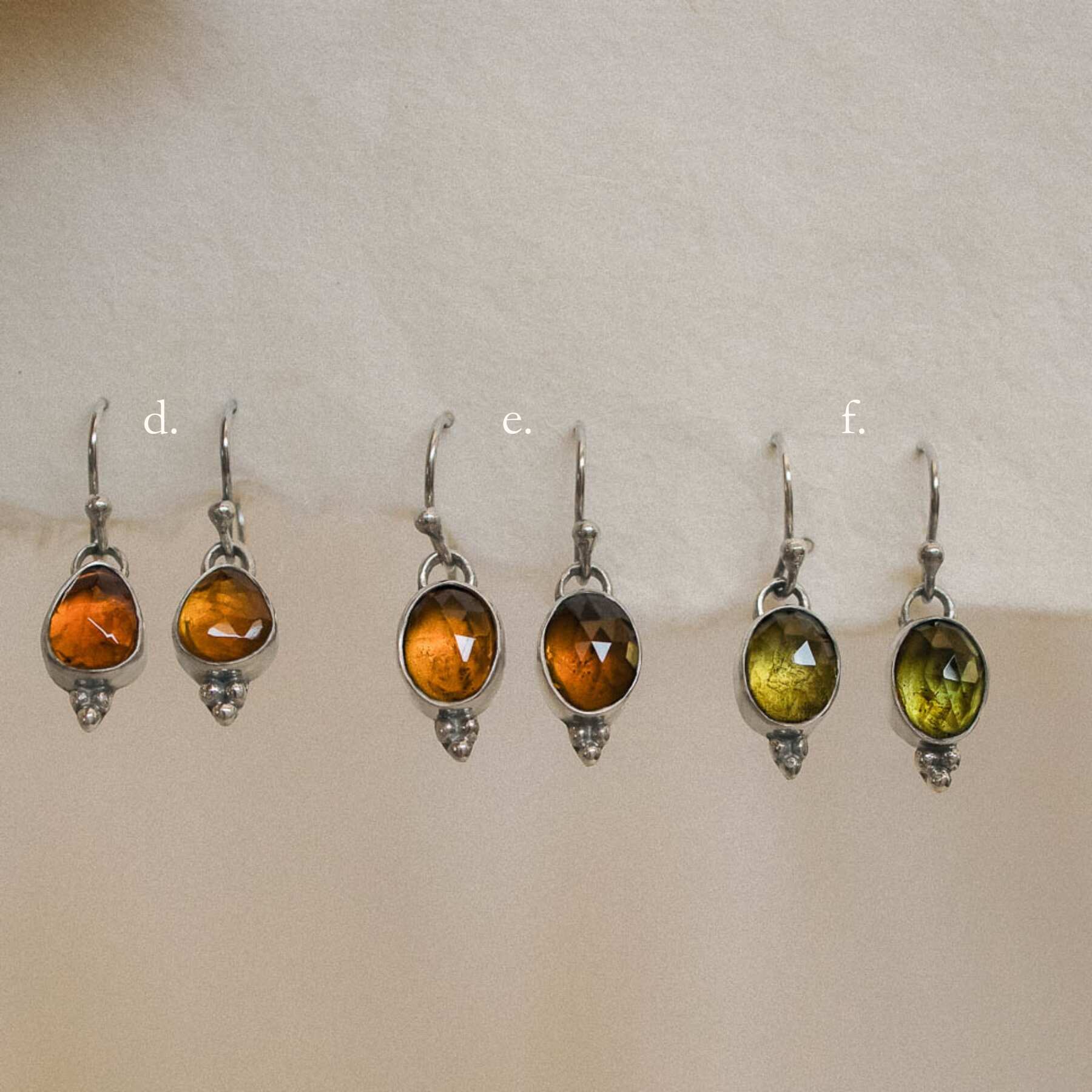 pairs of orange tourmaline earrings hanging on handmade paper options 2