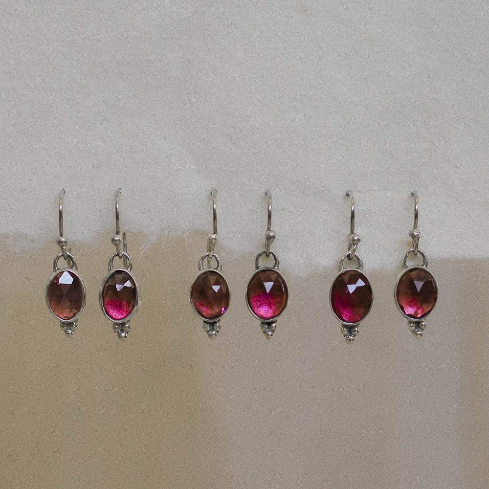 pairs of pink tourmaline earrings hanging on handmade paper
