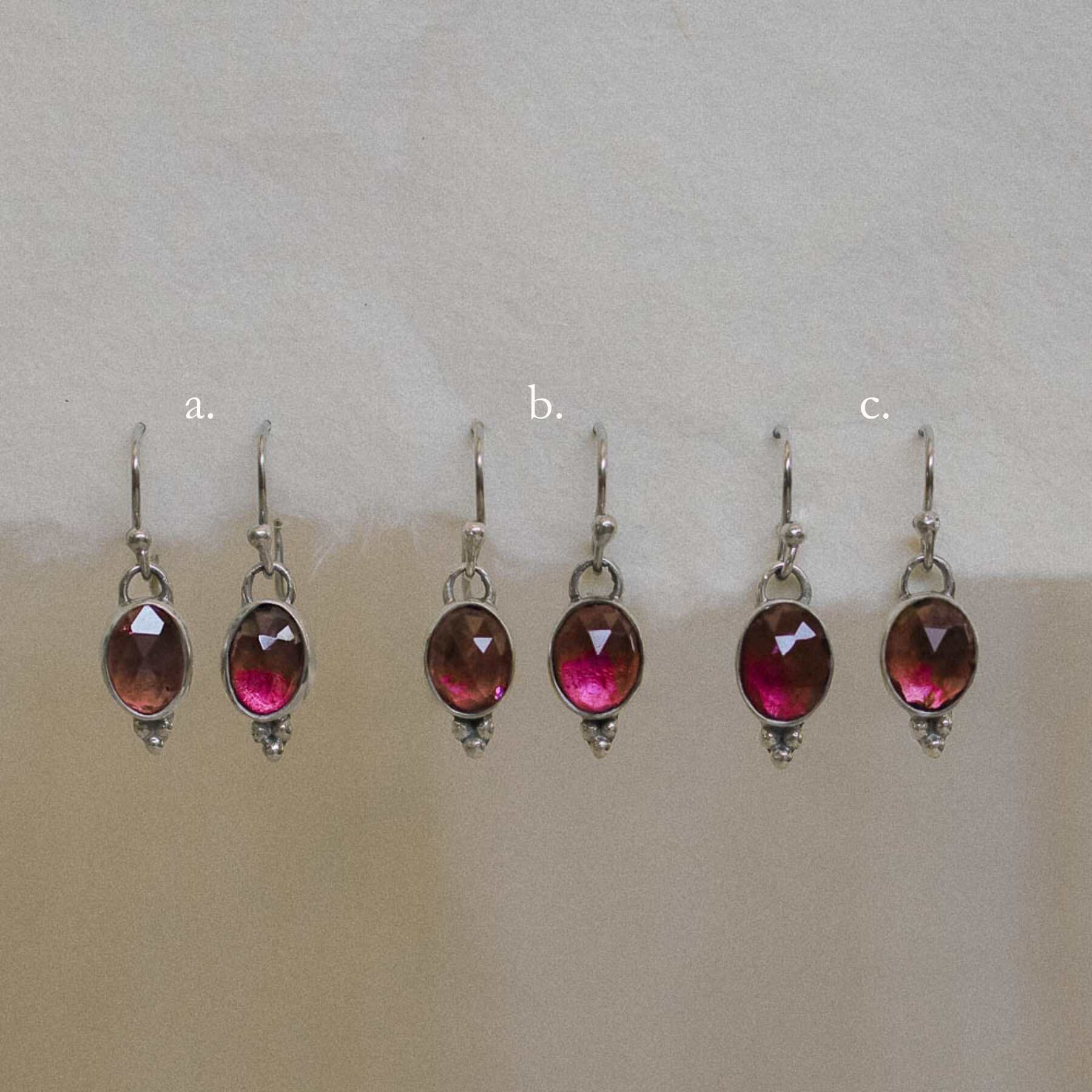 selection of pink tourmaline earring pairs dangling from handmade paper