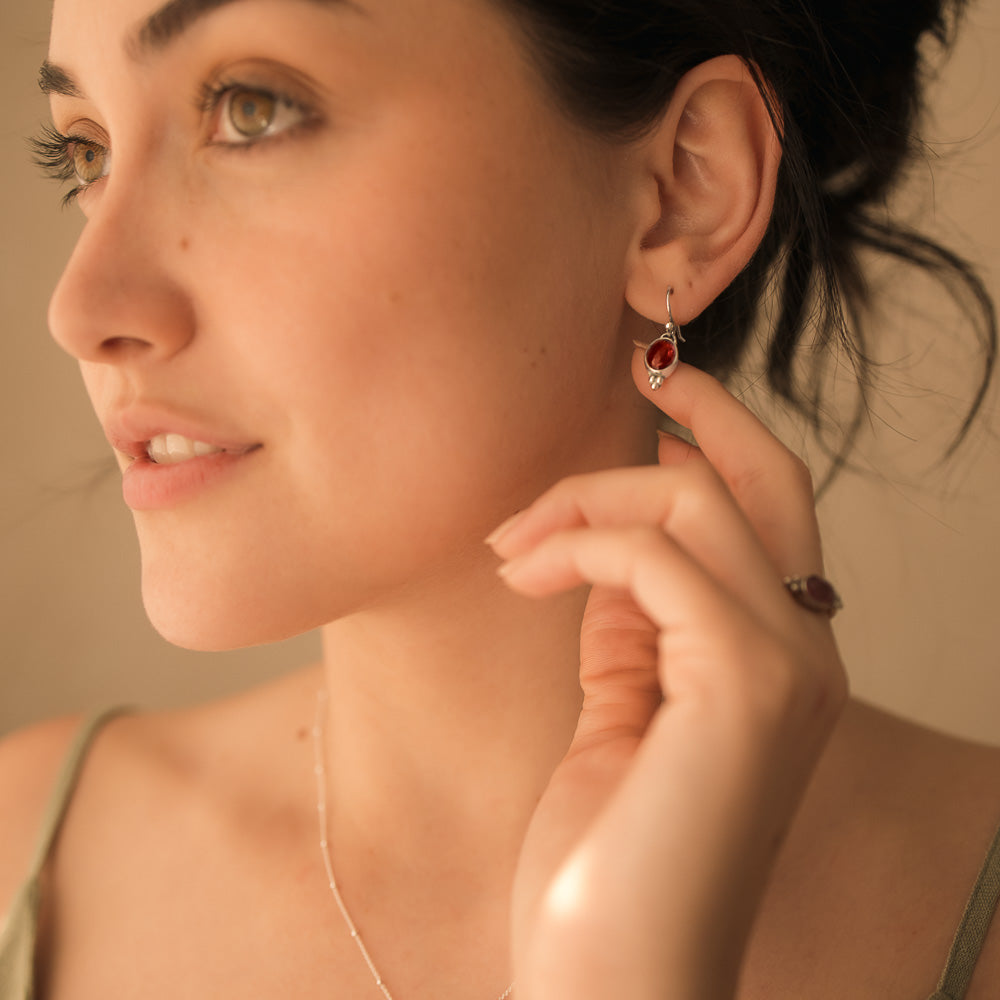 women touching pink tourmaline earrings