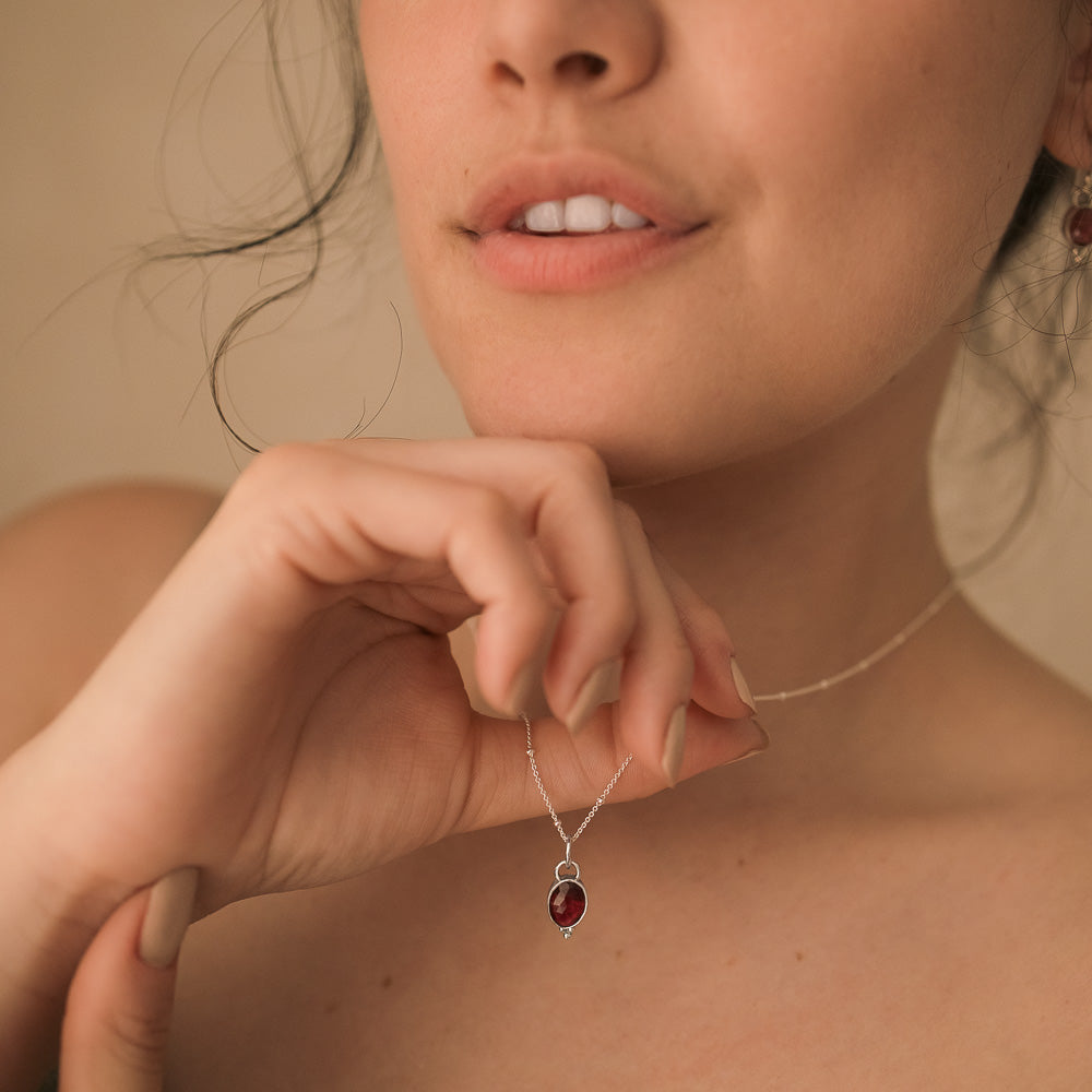 women holding a pink tourmaline pendant hanging on satellite chain