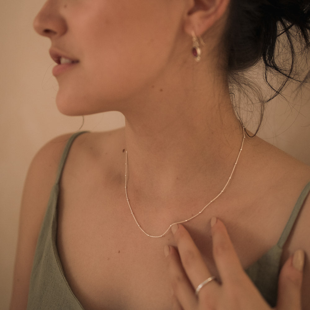 a woman wearing a silver satellite necklace chain