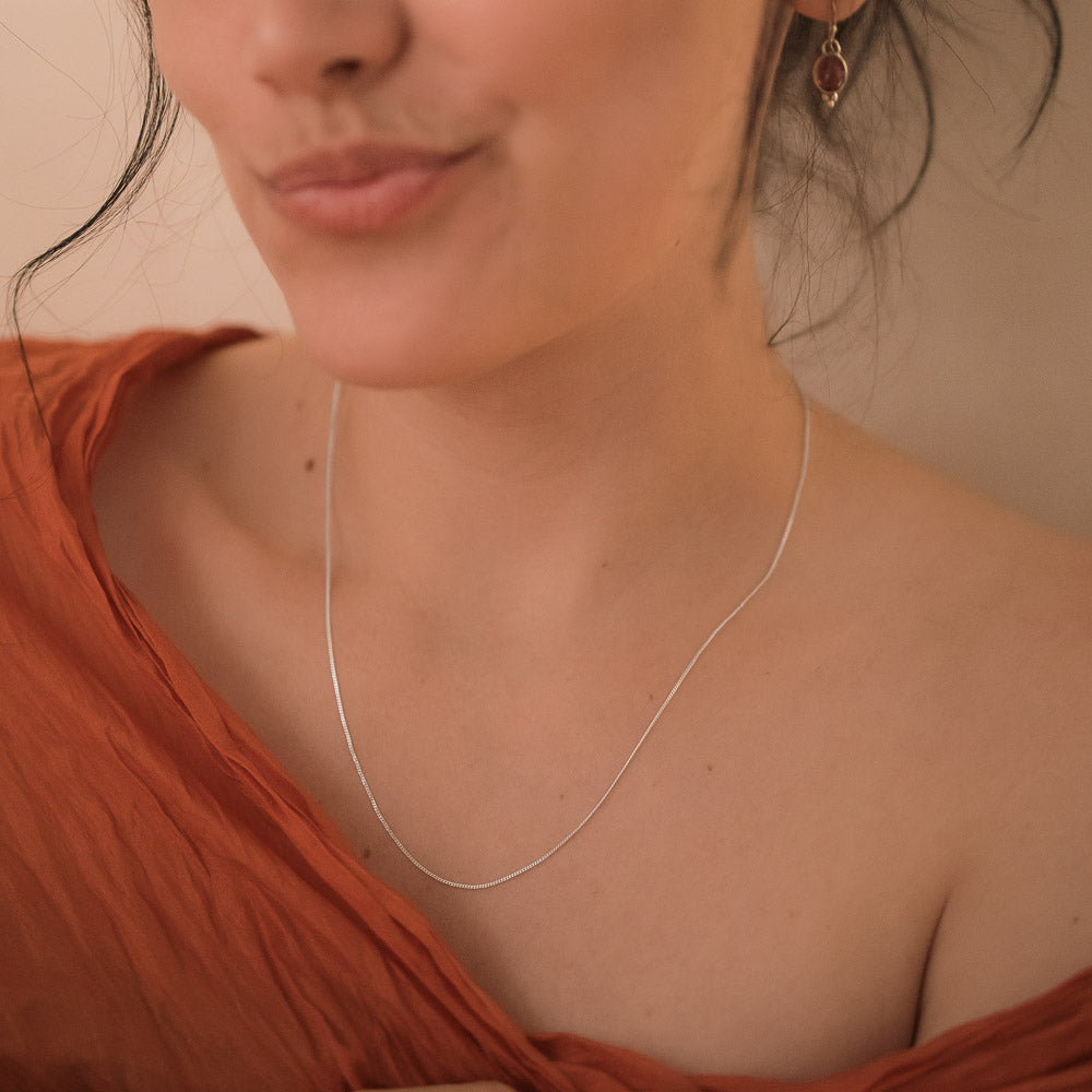 a woman wearing a fine silver chain necklace with silk scarf around her shoulders