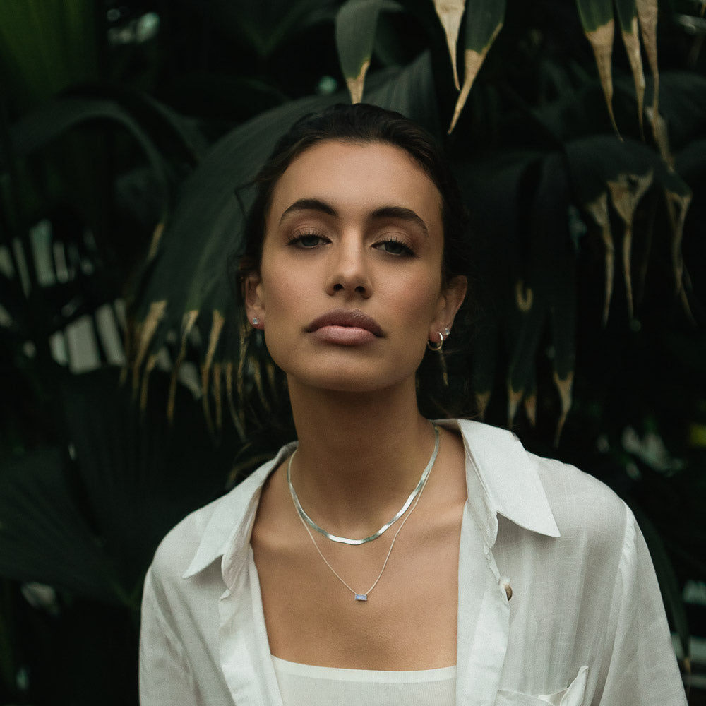 a woman wearing a silver herringbone necklace chain