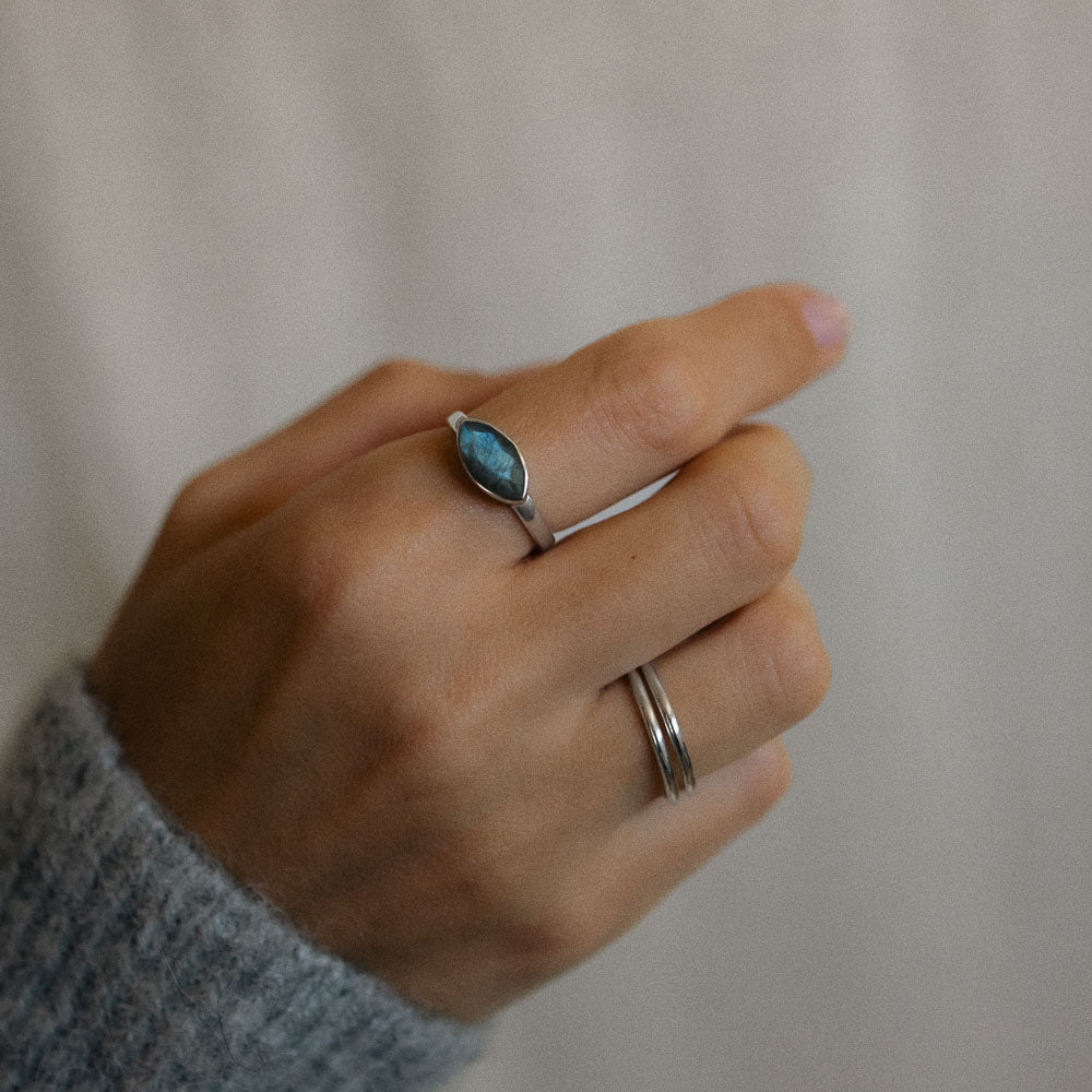 a woman wearing two sterling silver band rings and a labradorite silver ring