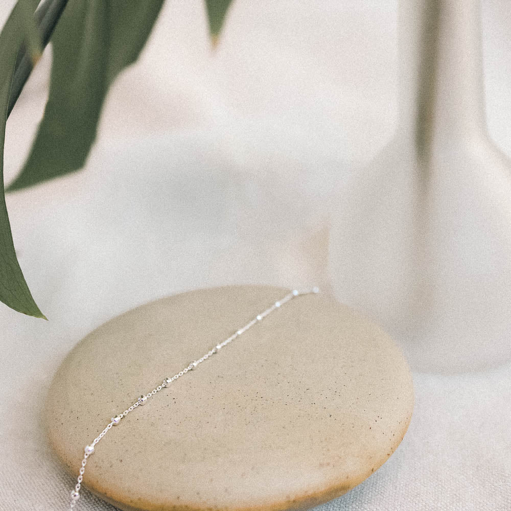 a silver anklet on a ceramic dish