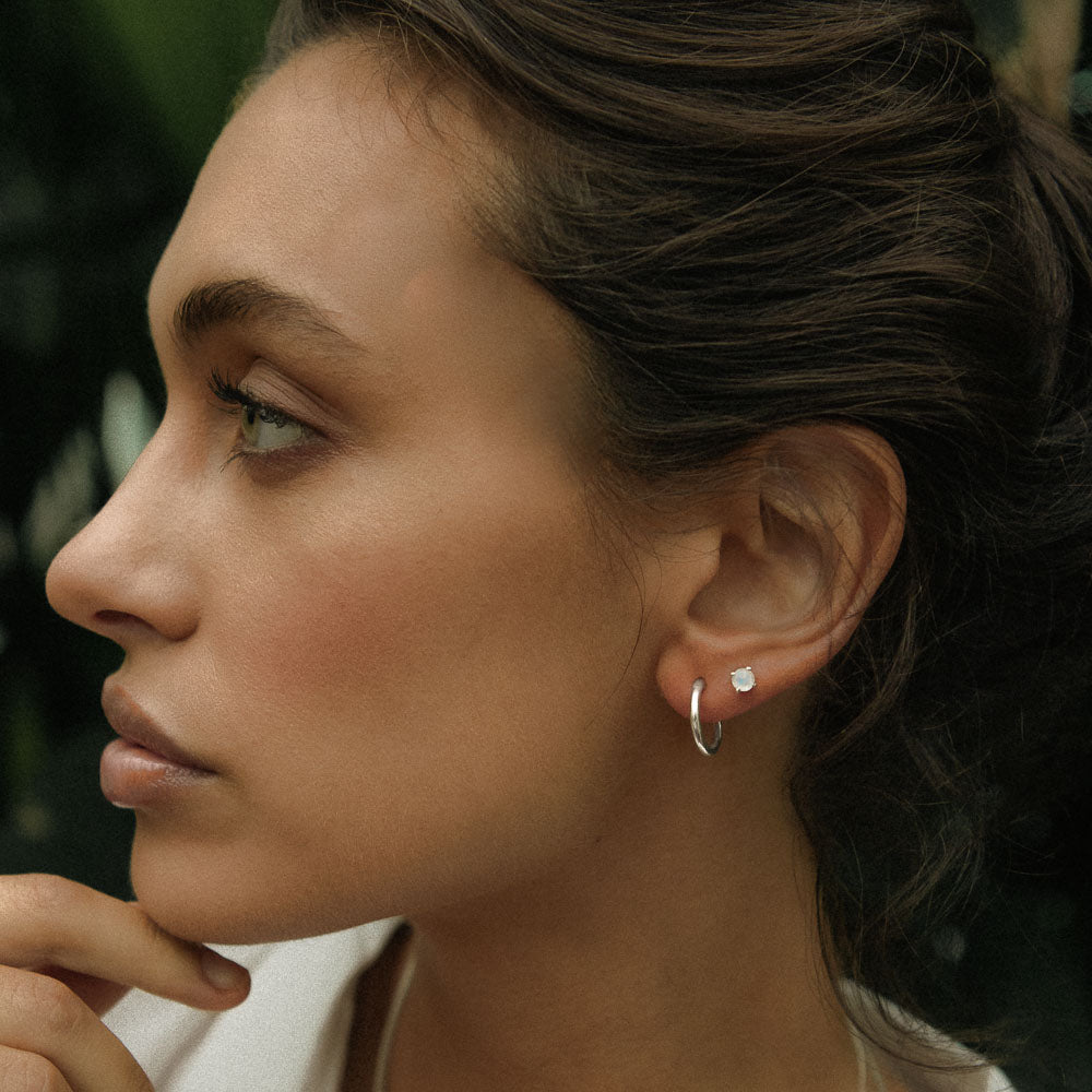 a woman wearing silver jewellery polished hoop earrings looking to the side