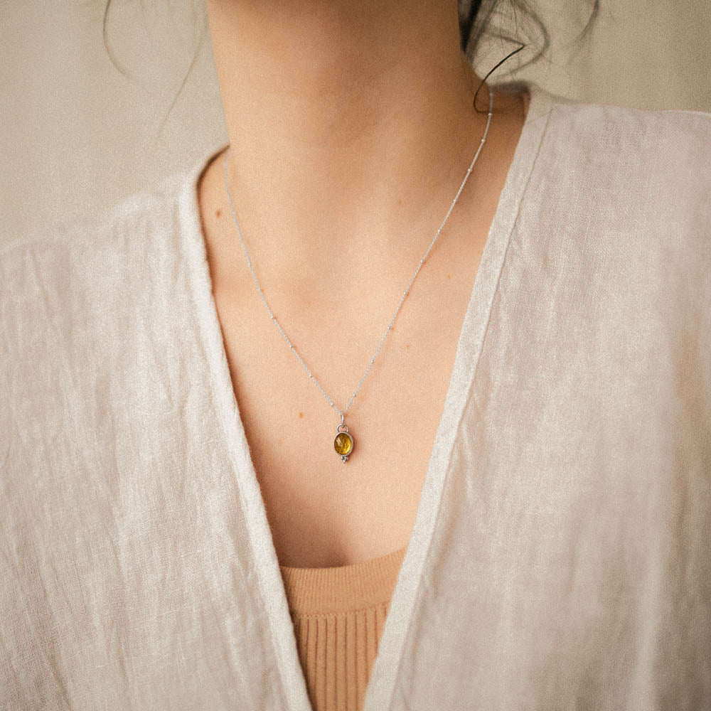 women wearing yellow tourmaline pendant on satellite chain in linen clothing