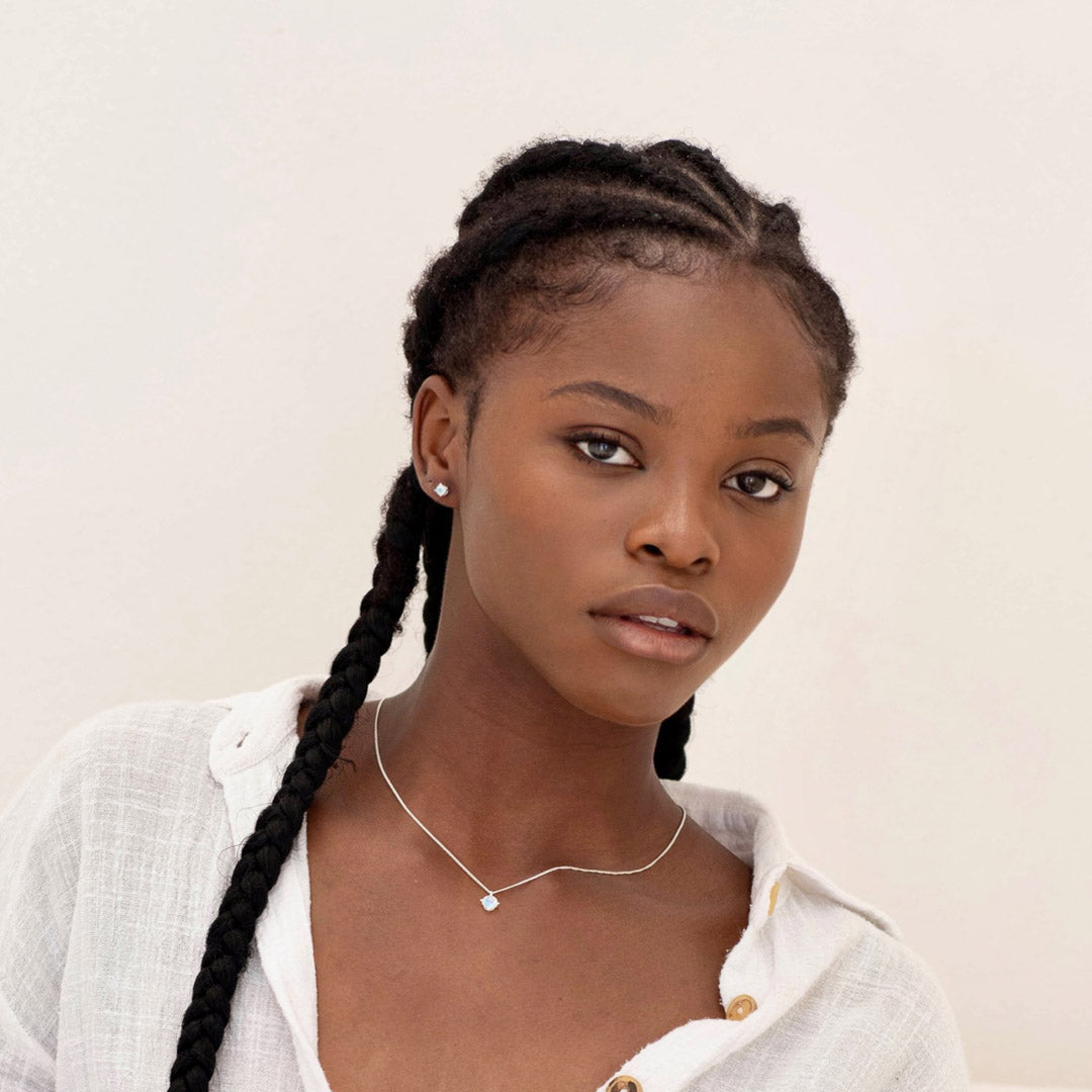 woman looking at camera wearing round small moonstone earrings and necklace
