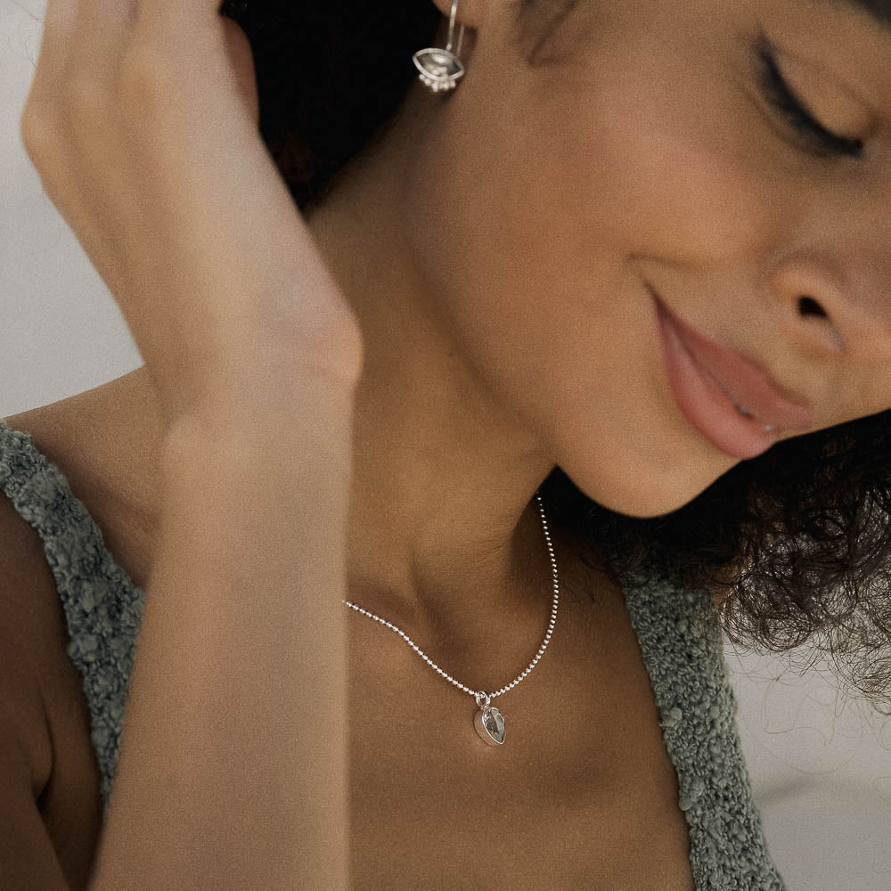Woman wearing a silver necklace with a high clarity sparkling Green Amethyst (Prasiolite) pendant, close-up shot.