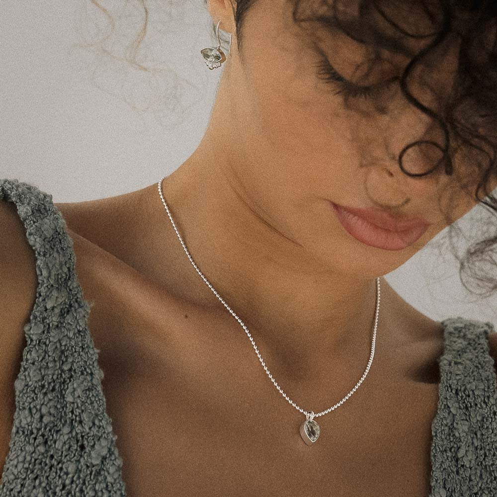 Woman wearing a silver necklace with a Green Amethyst (Prasiolite) pendant against a neutral background