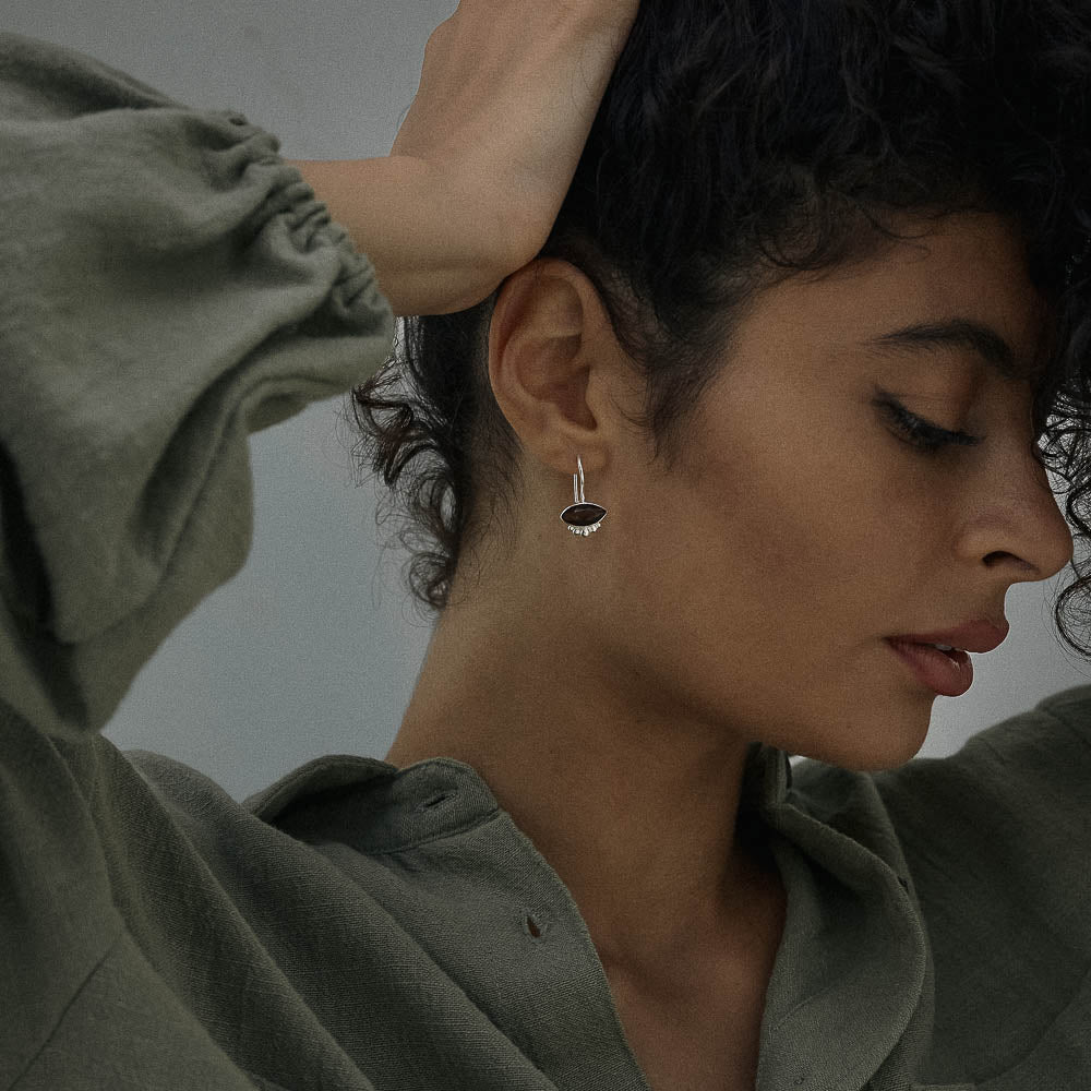 Woman wearing a natural Smokey Quartz earring with a neutral background