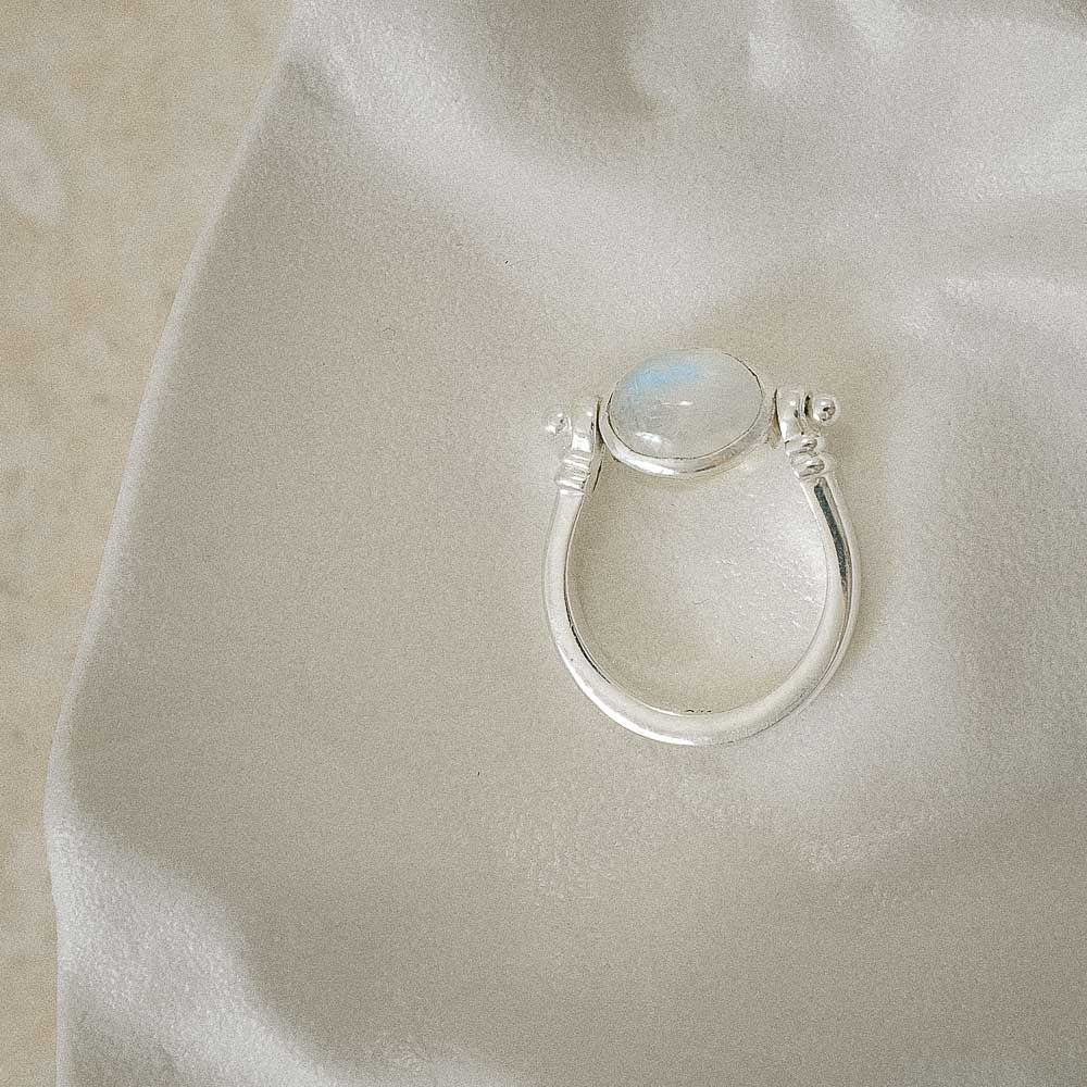 Silver ring with a moonstone on a light fabric background