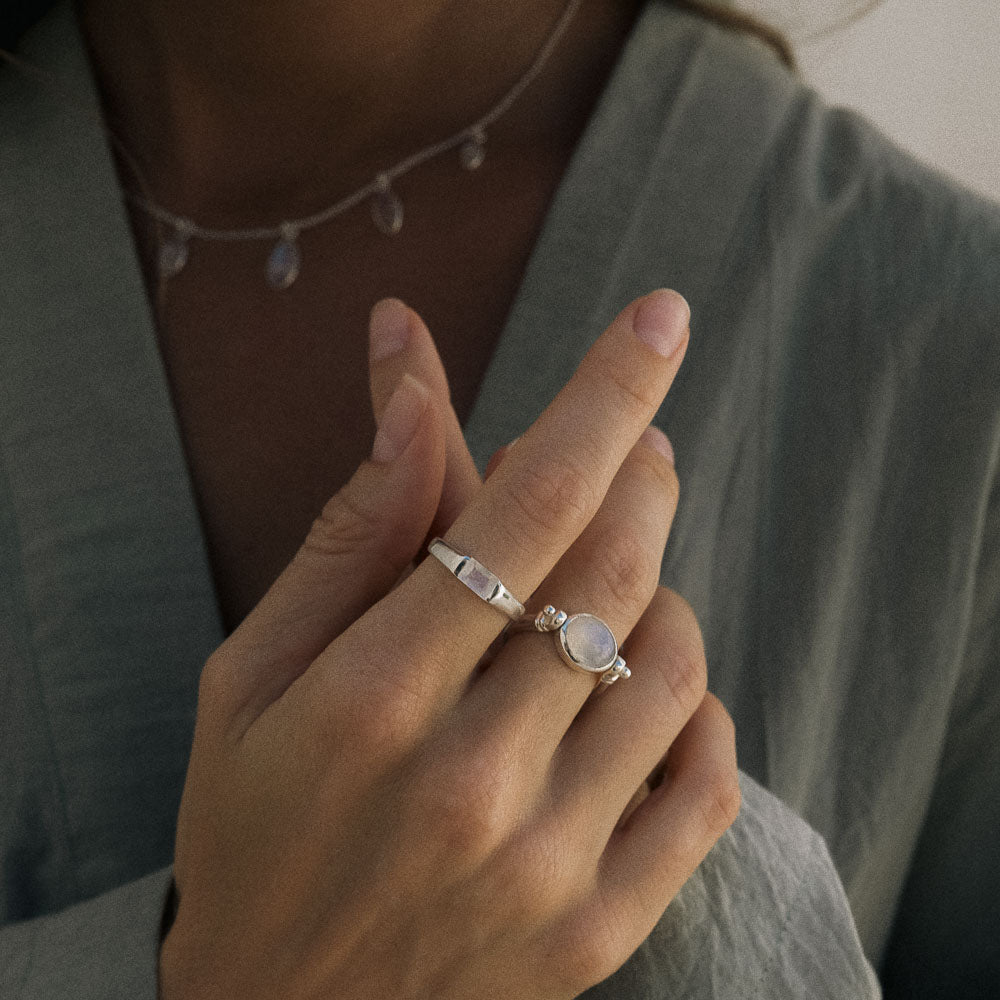Close-up of a hand wearing silver rings with a gemstone, blurred background