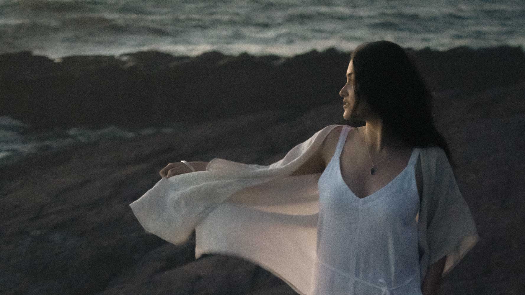 an earthy woman looking out to the ocean wearing silver opal jewellery