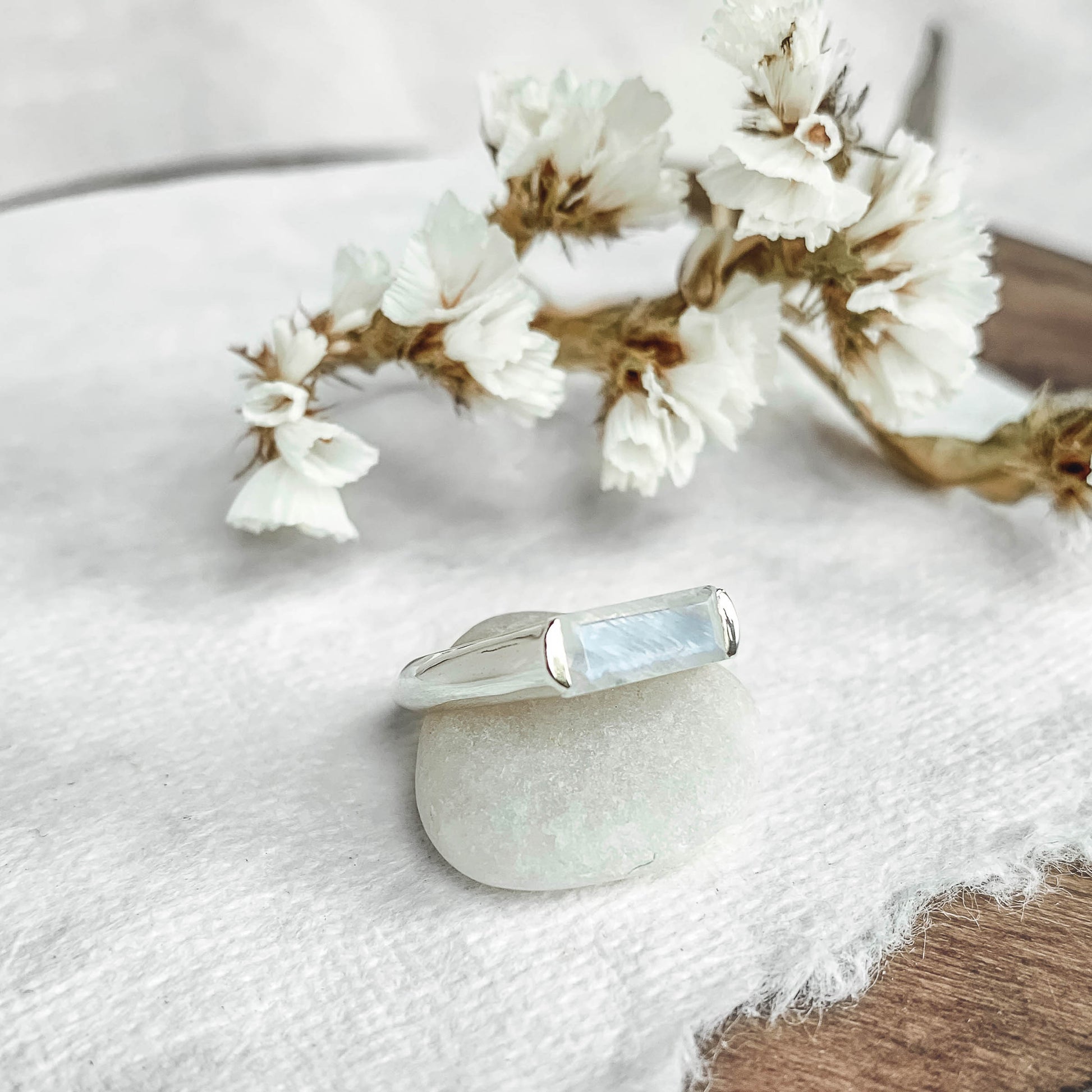 large baguette moonstone silver ring on white paper with flowers