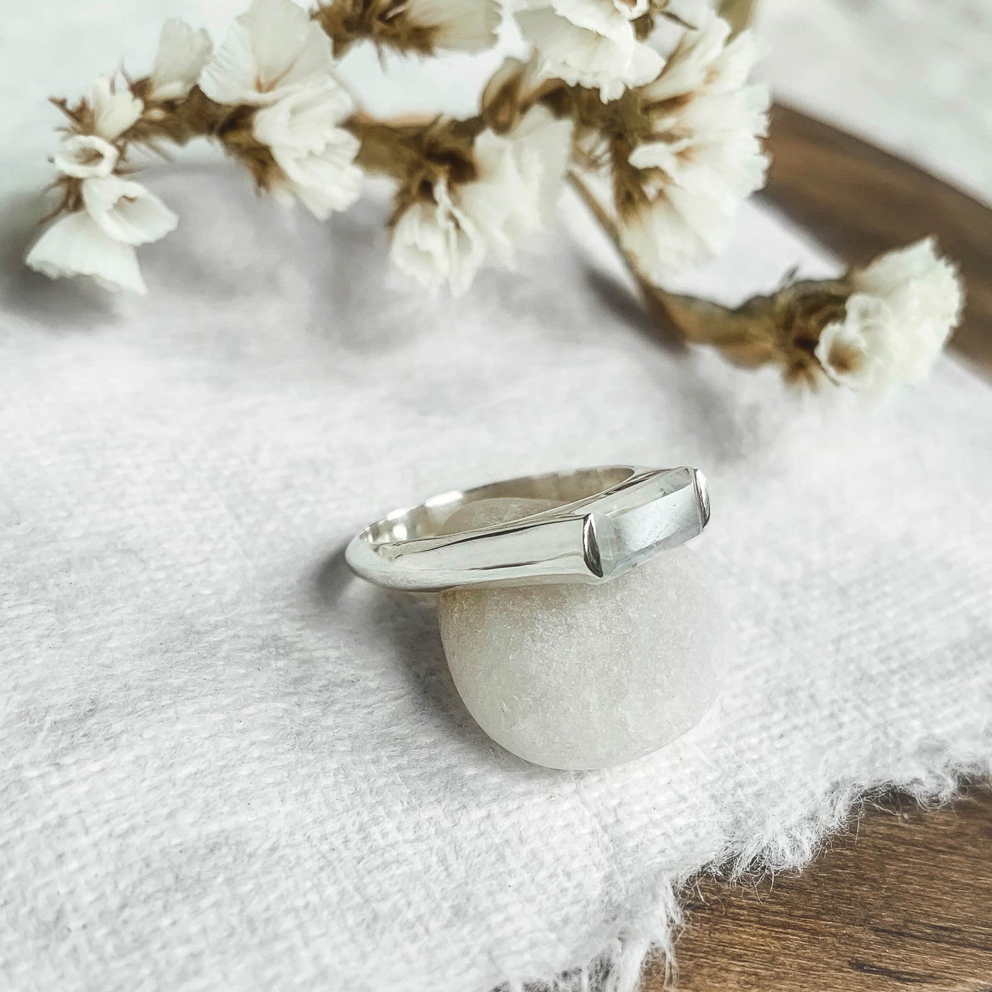 large baguette moonstone silver ring side view  on white paper with flowers