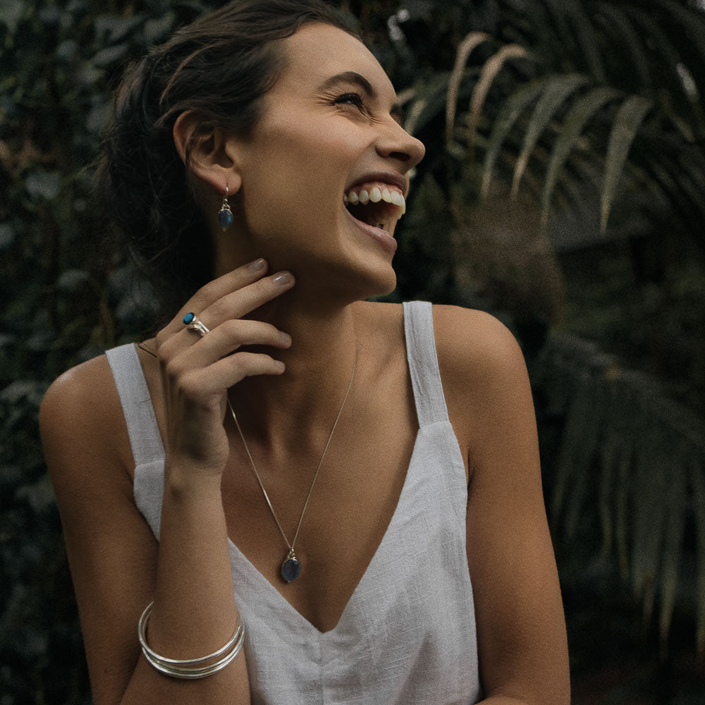 a laughing woman wearing symbolic silver oval labradorite ring on finger