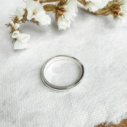 one moonstone solitaire ring resting on natural paper with white flowers