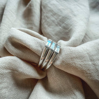 side view of three midi baguette moonstone silver rings on linen