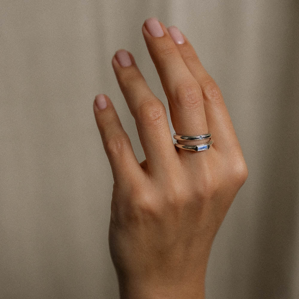 a moonstone baguette and round solitaire ring on hand