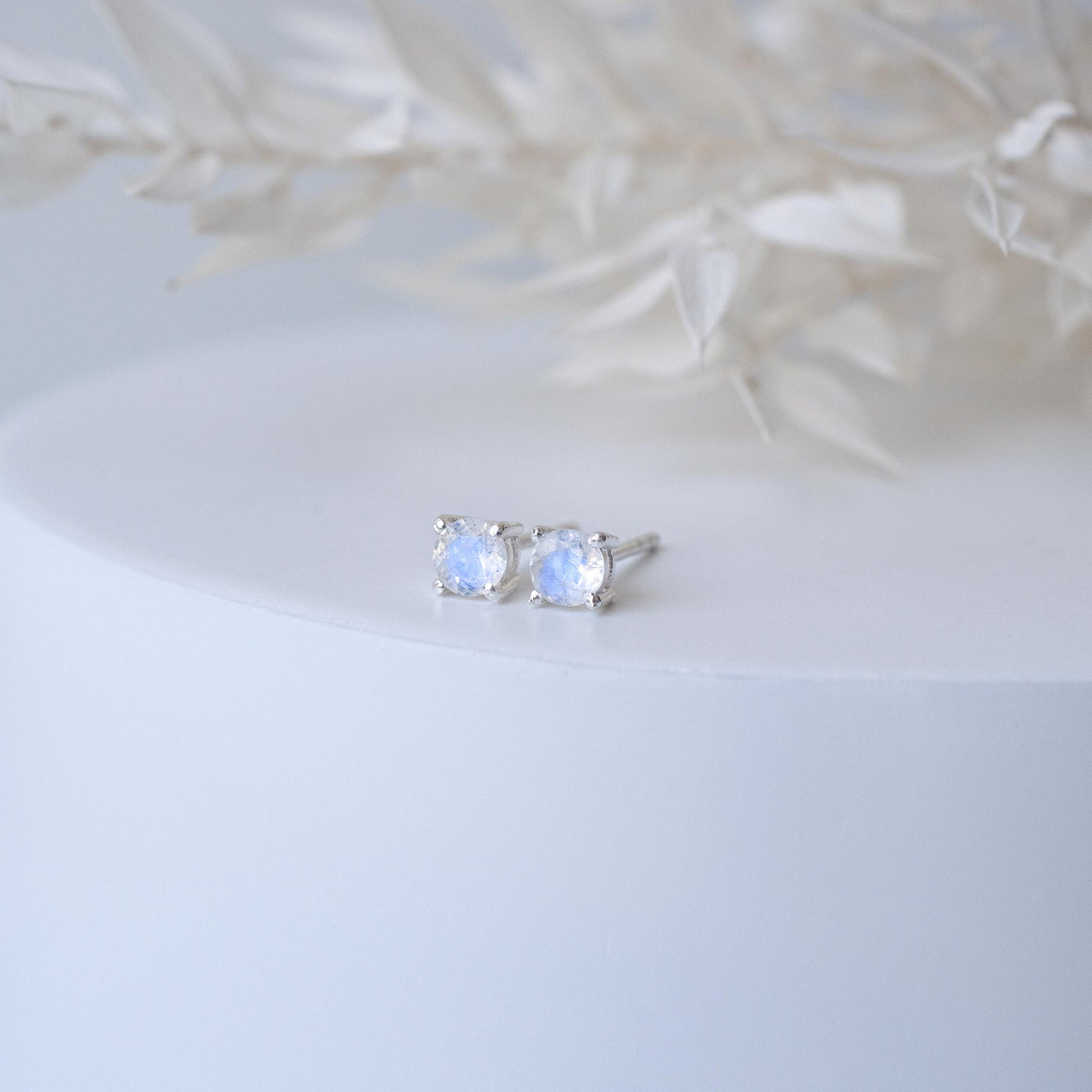 small sparkling blue mini studs on white cylinder with preserved flowers in background