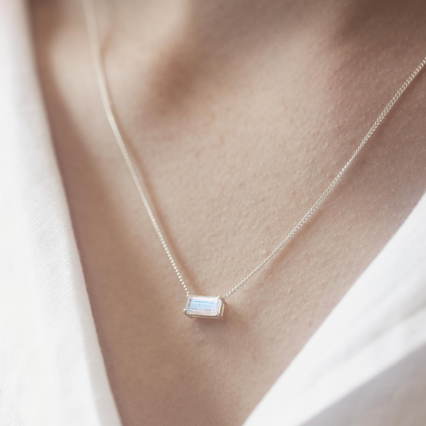 horizontal rainbow moonstone pendant necklace on model with white shirt