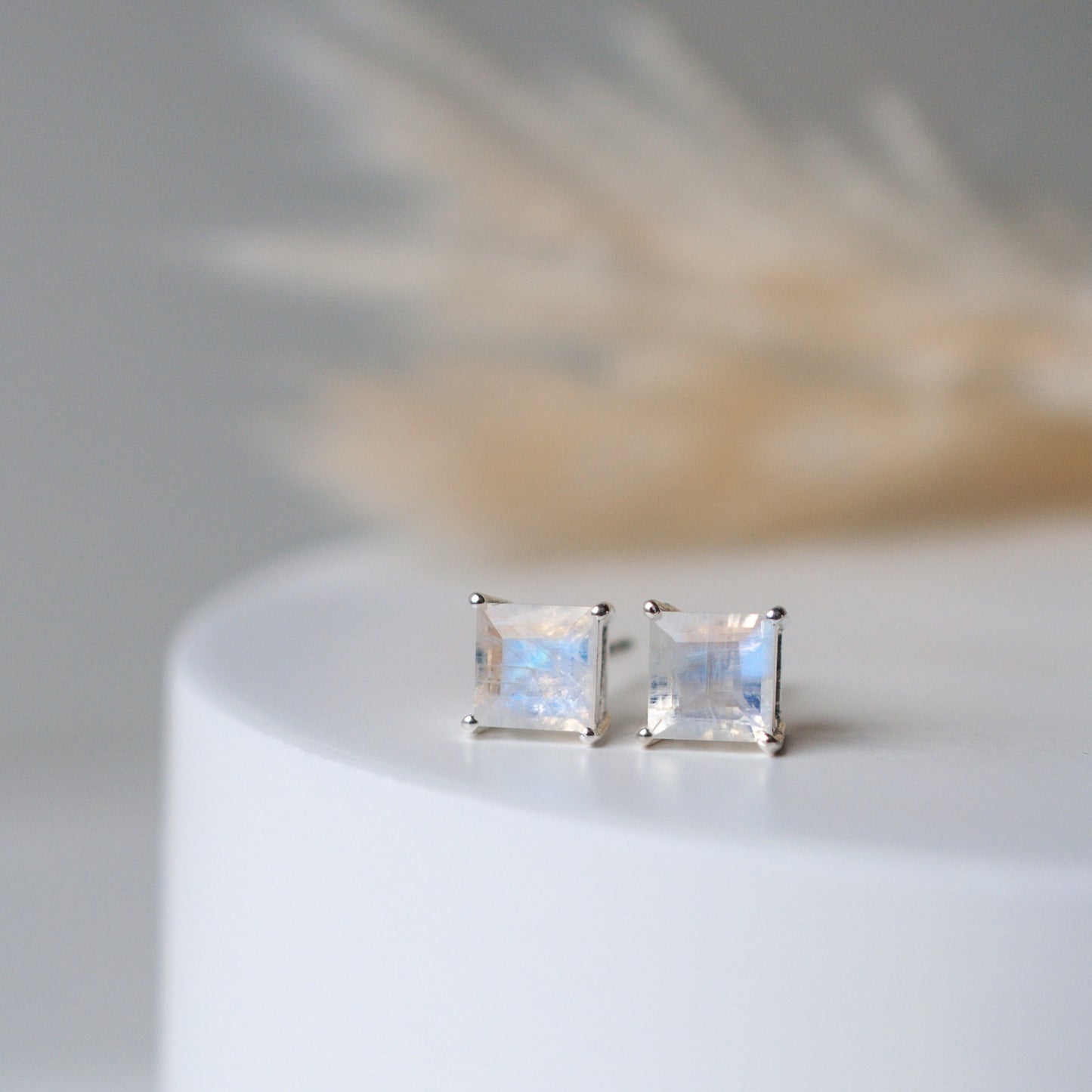 Large square rainbow moonstone silver studs  on white cylinder with wheat in background